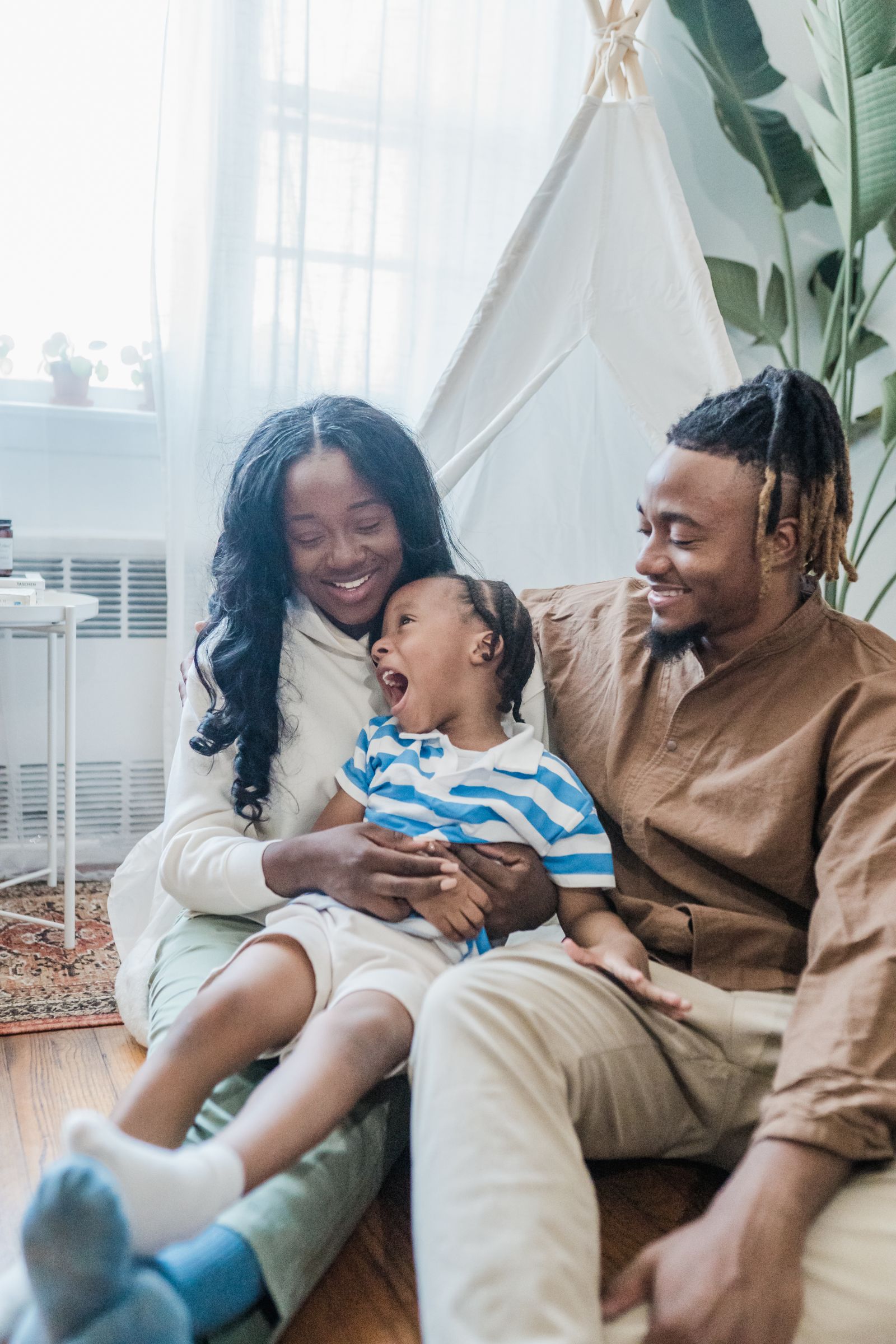 Two parents sitting on the floor at home with their young child