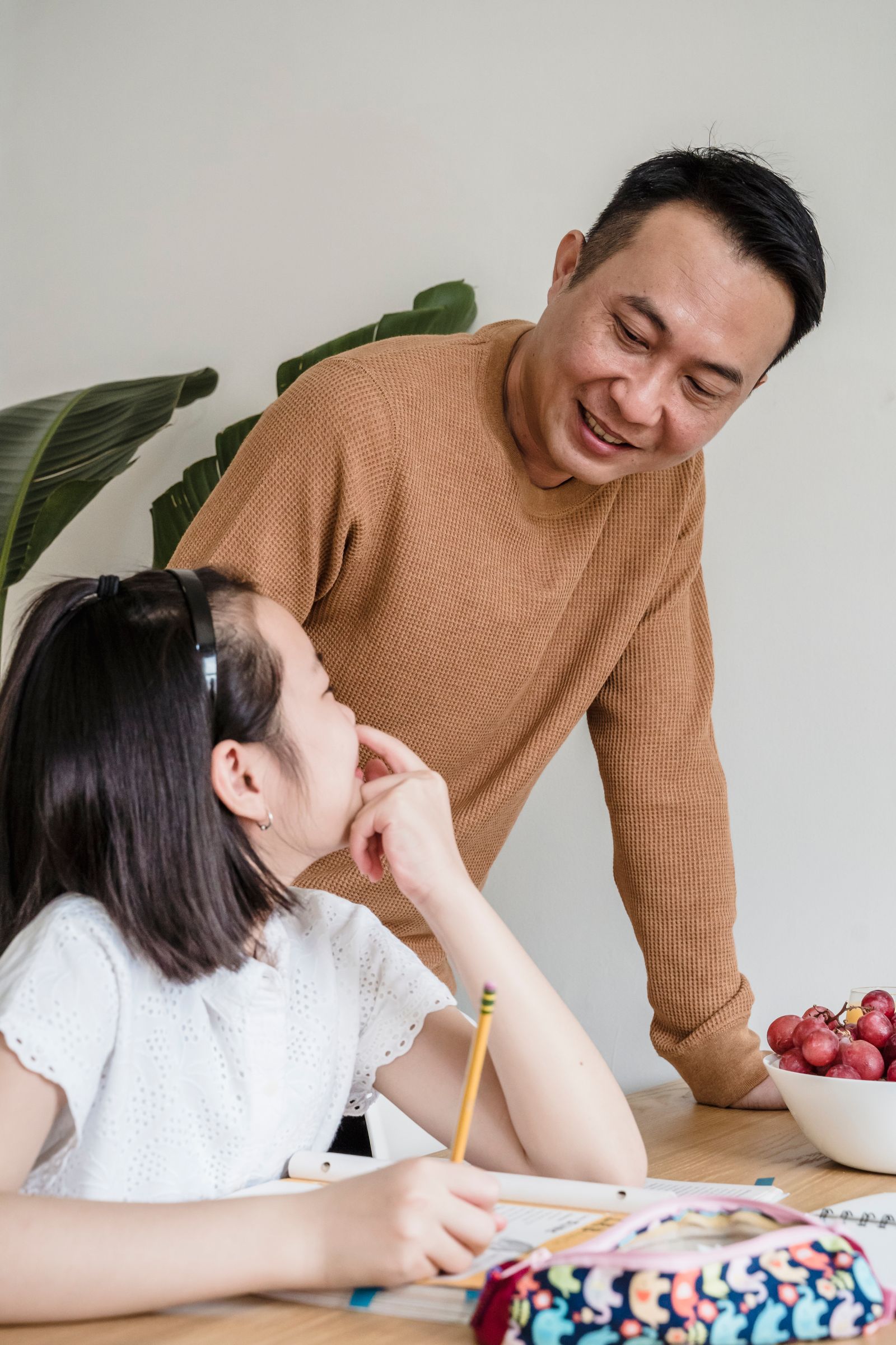 A father helping his daughter with schoolwork at the kitchen table