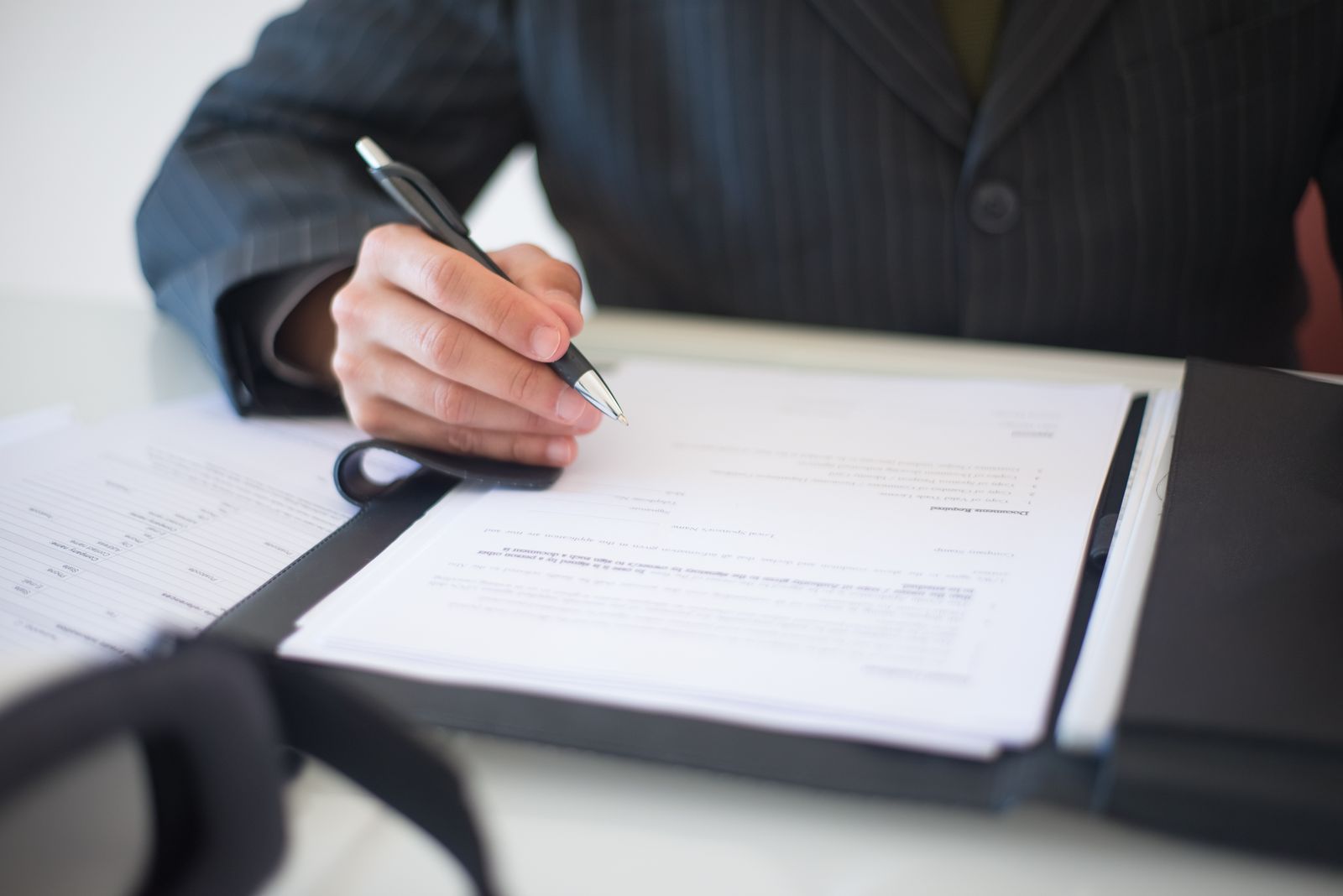 A hand completing a regulatory filing at a desk